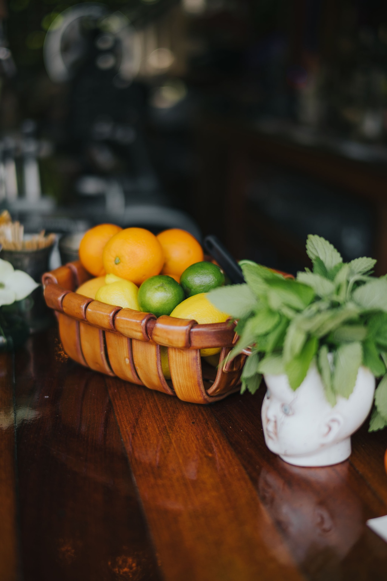A basket of oranges, lemons, and limes with fresh mint on the bar