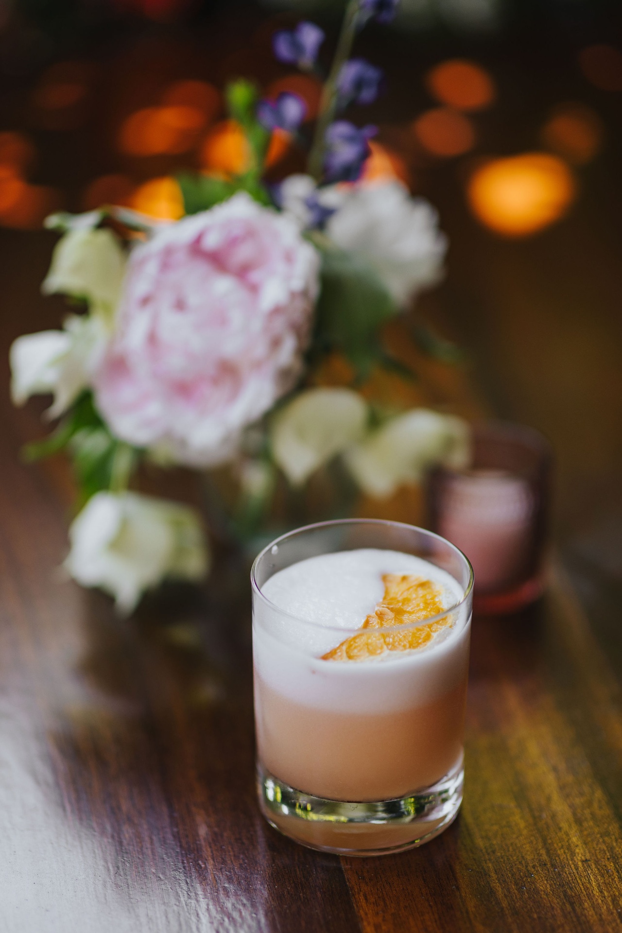 A pisco-style sour beside fresh flowers