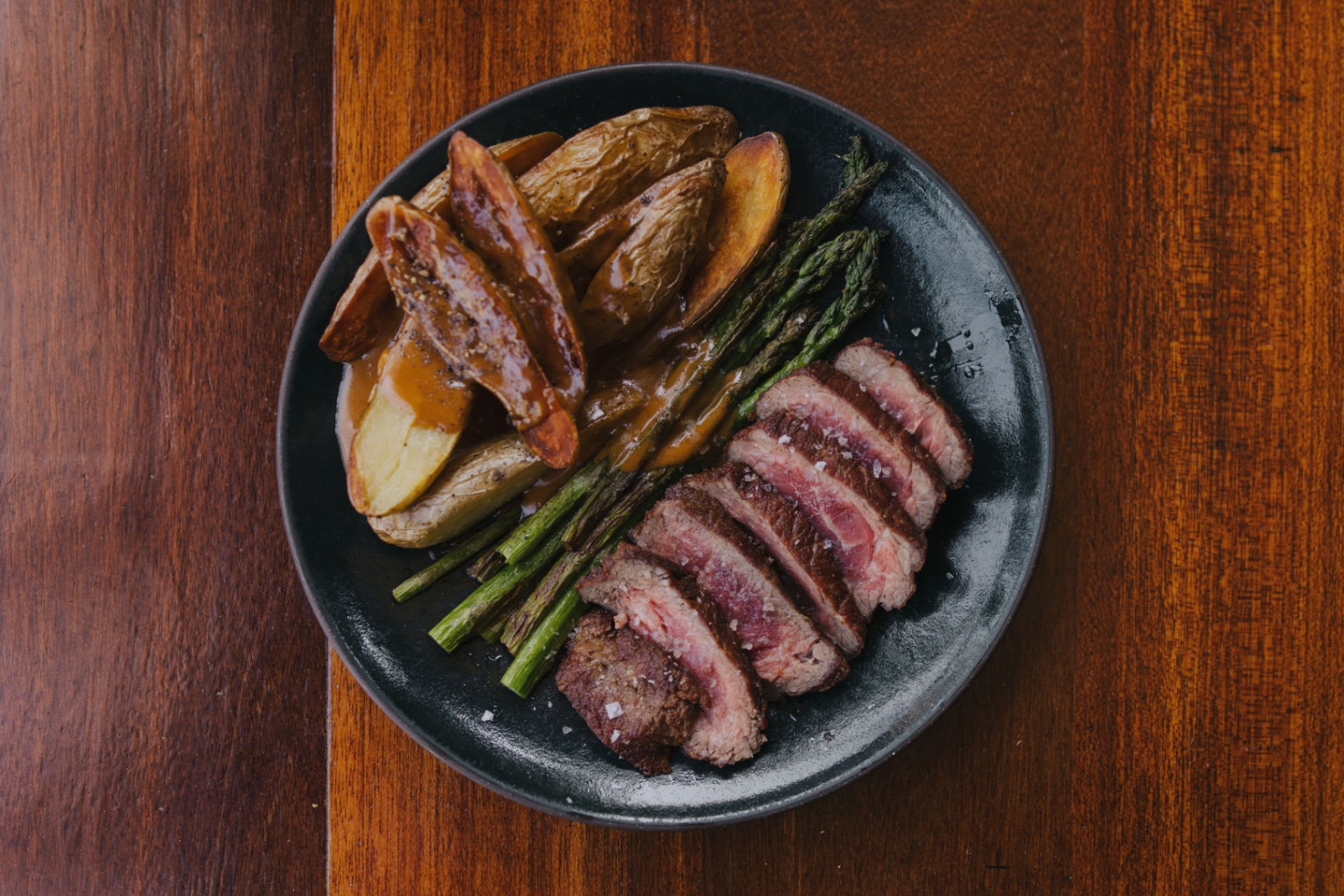 Sliced steak with roasted fingerlings, asparagus, and pan jus